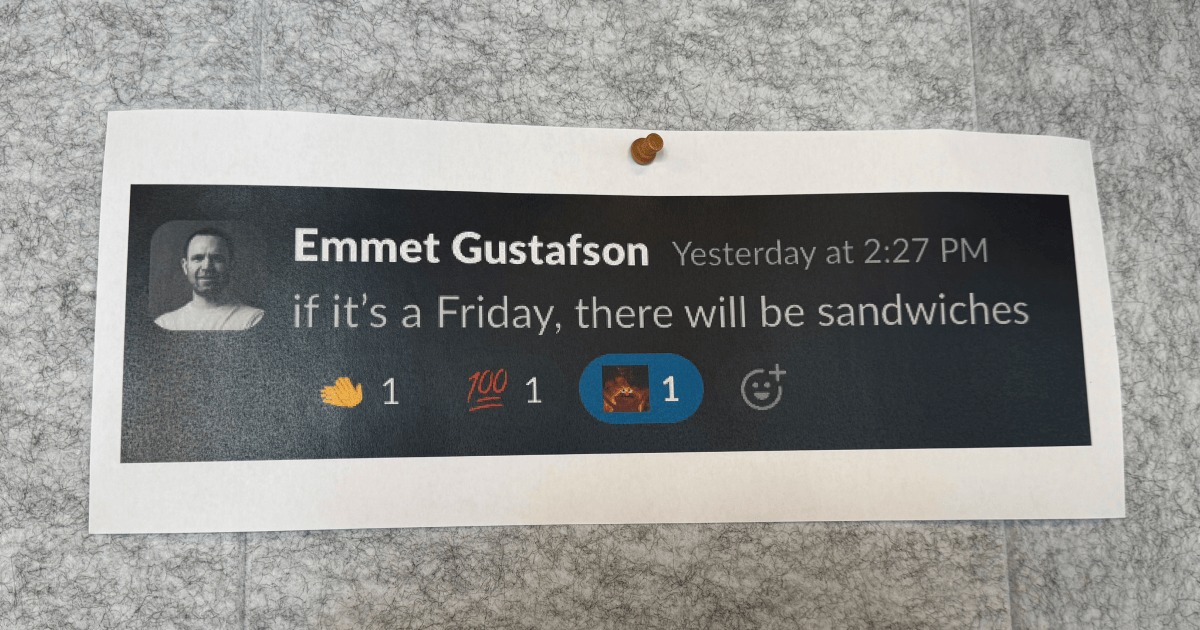 A printed Slack message on a board saying "if it's a Friday, there will be sandwiches"