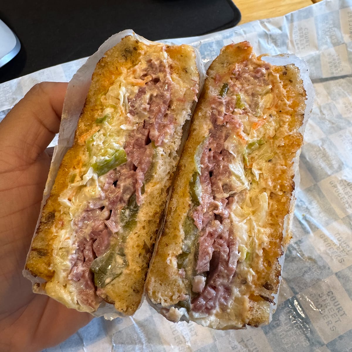 A cut sandwich with corned beef, swiss cheese, coleslaw, full sour pickles, and comeback sauce on Orwasher’s rye bread.